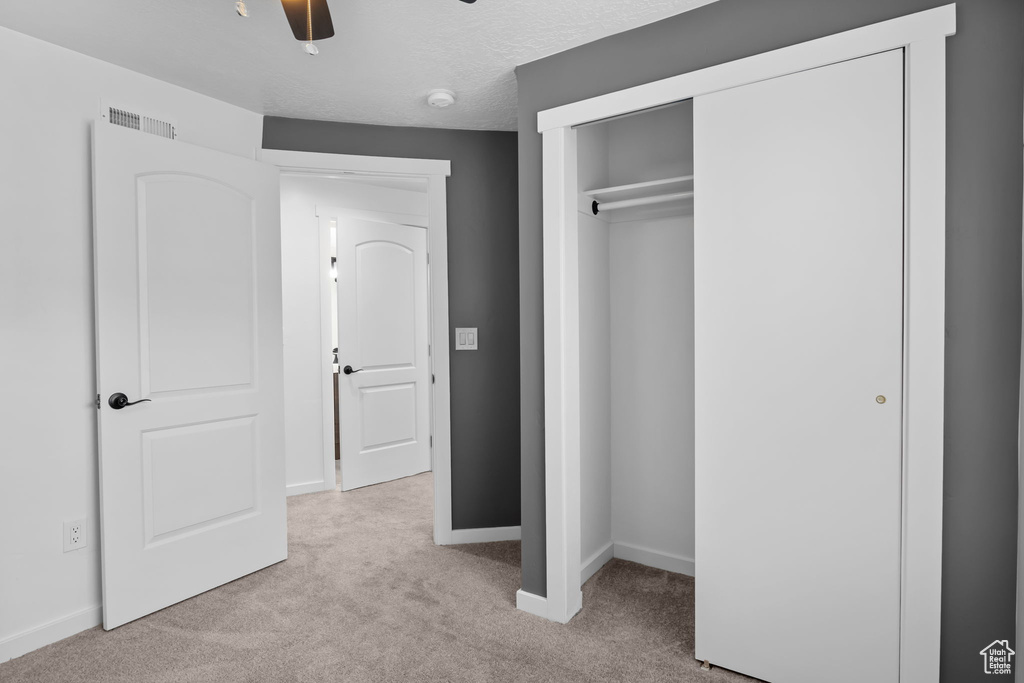 Unfurnished bedroom with carpet, baseboards, a closet, and ceiling fan