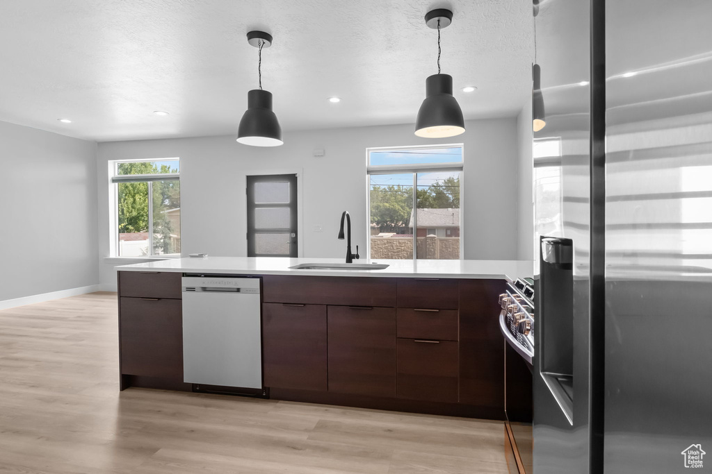 Kitchen with appliances with stainless steel finishes, a sink, modern cabinets, light countertops, and recessed lighting