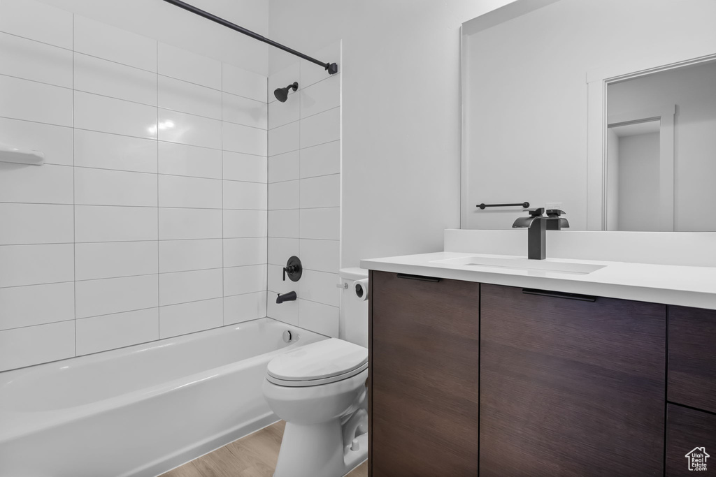 Full bath featuring vanity, toilet, shower / bathtub combination, and wood finished floors