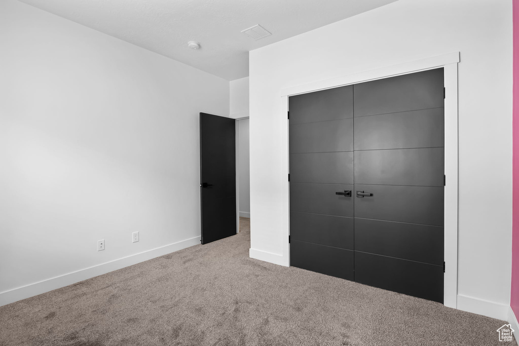Unfurnished bedroom with carpet floors, baseboards, and a closet
