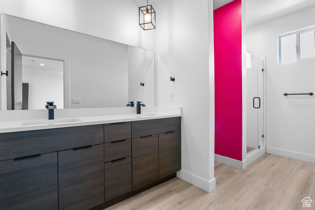 Full bath featuring wood finished floors, double vanity, baseboards, and a shower stall