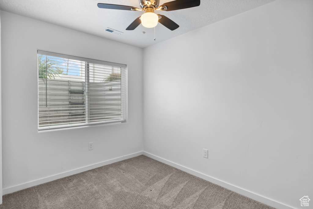 Carpeted empty room featuring baseboards and ceiling fan