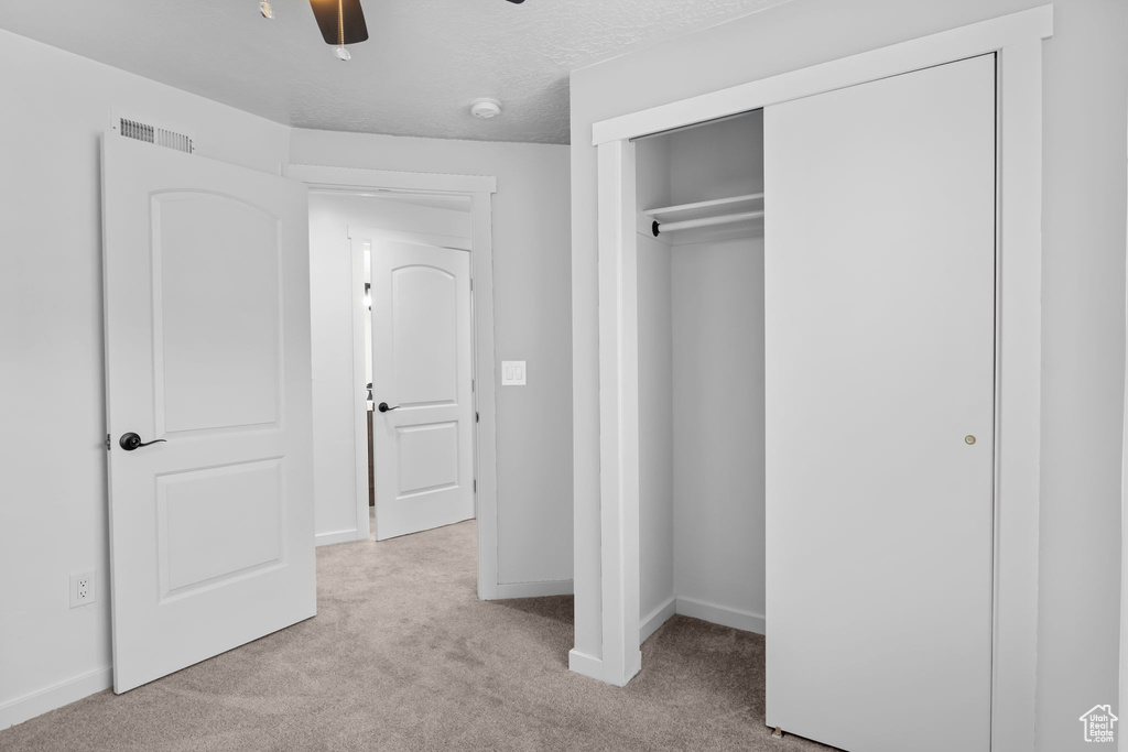 Unfurnished bedroom with carpet floors, baseboards, a closet, and a ceiling fan