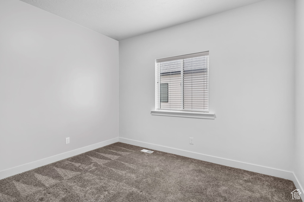 Unfurnished room with dark colored carpet and baseboards