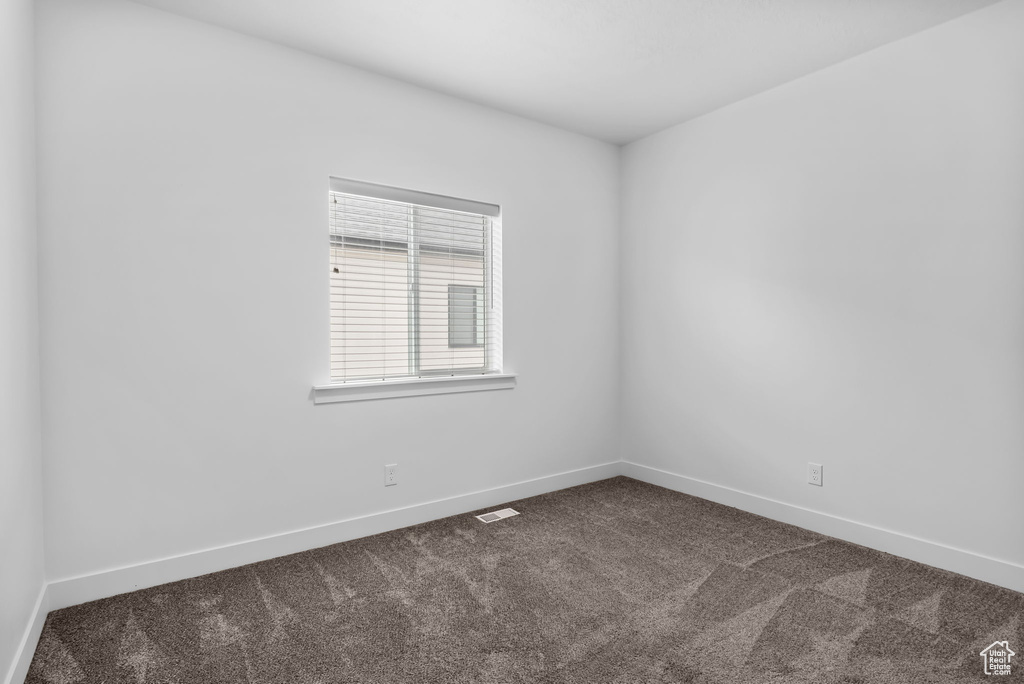Empty room featuring dark colored carpet and baseboards
