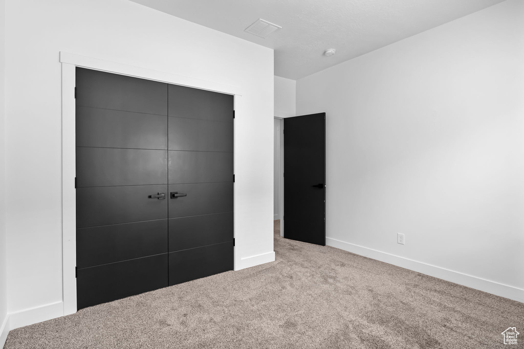 Unfurnished bedroom with carpet flooring, a closet, and baseboards