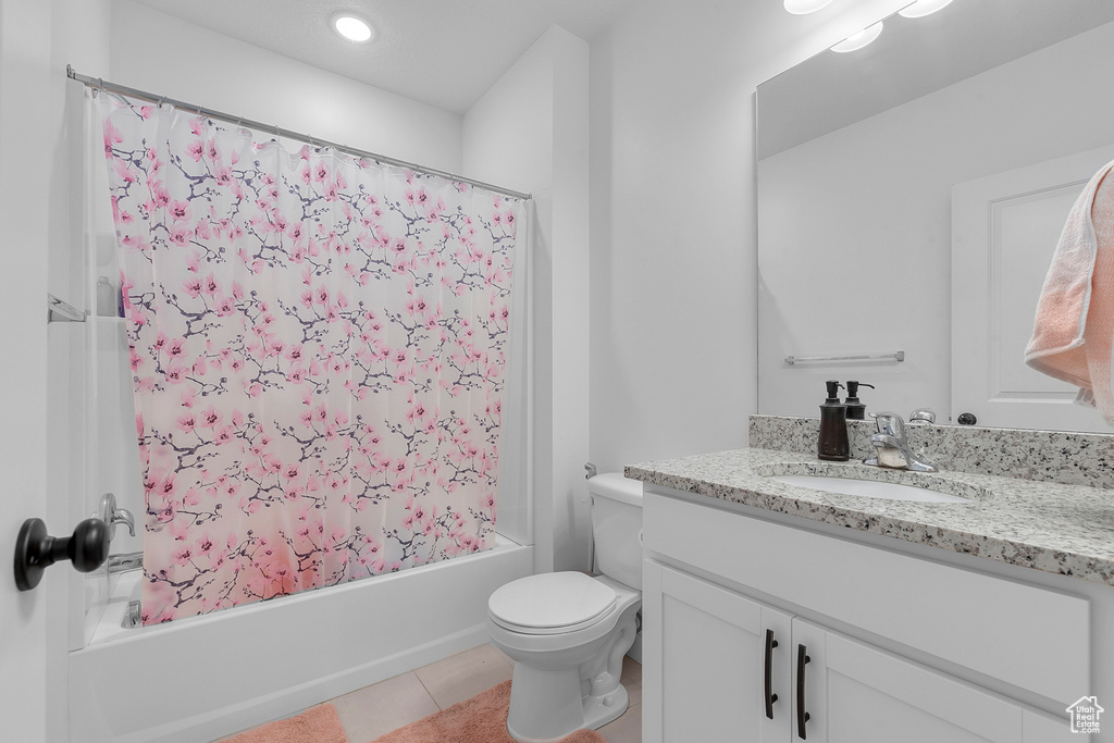 Full bath featuring vanity, shower / bathtub combination with curtain, tile patterned flooring, and toilet