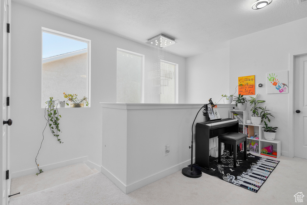Miscellaneous room featuring carpet floors, a textured ceiling, baseboards, and an upstairs landing