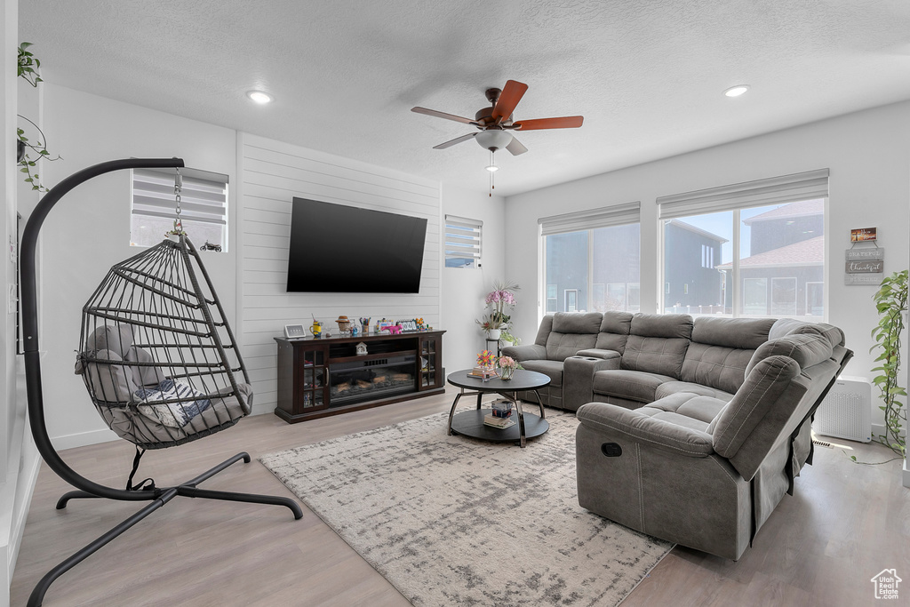 Living area featuring wood finished floors, a ceiling fan, a textured ceiling, and recessed lighting