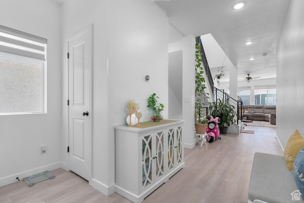 Hallway with light wood-style flooring, recessed lighting, and stairway