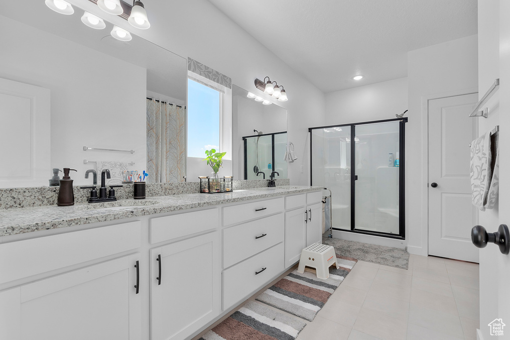 Full bathroom featuring a shower stall, double vanity, and tile patterned floors