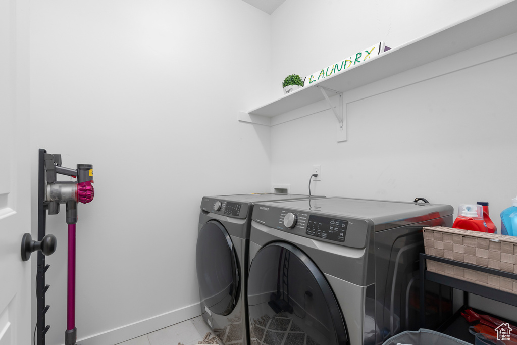 Laundry area with independent washer and dryer, baseboards, and light tile patterned flooring
