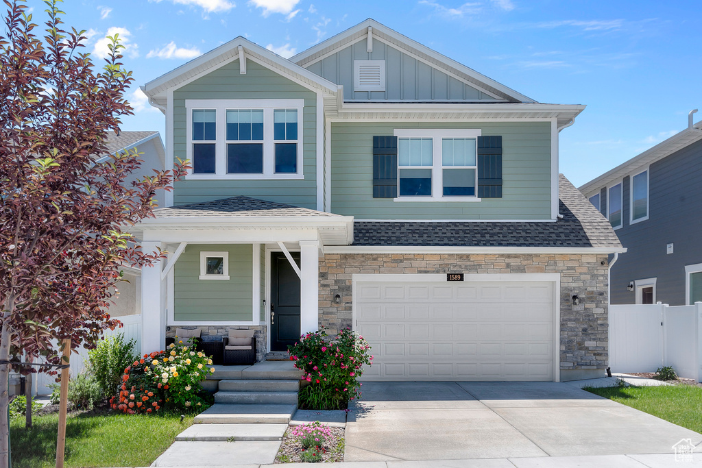 Craftsman inspired home featuring covered porch, board and batten siding, a shingled roof, and concrete driveway