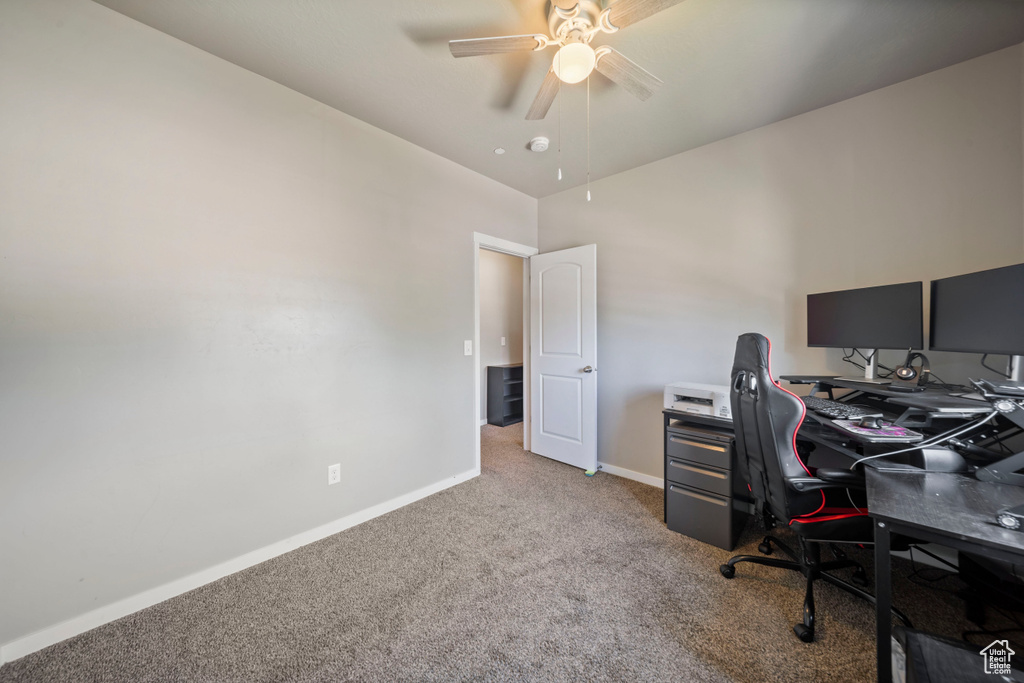 Home office featuring carpet flooring, ceiling fan, and baseboards