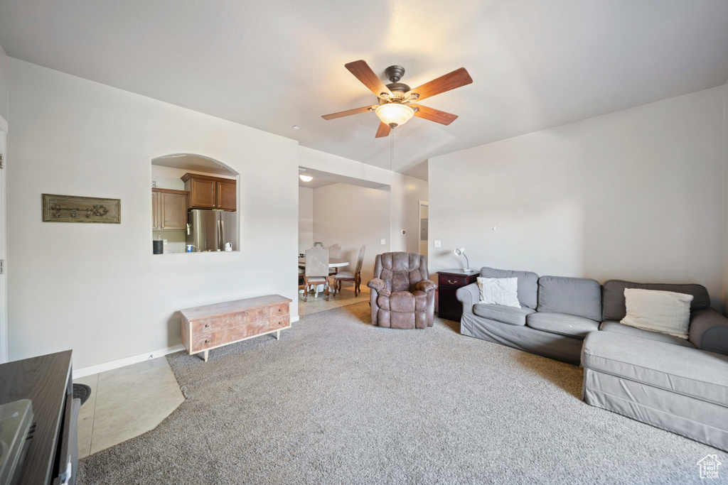 Living area with ceiling fan, carpet floors, and arched walkways