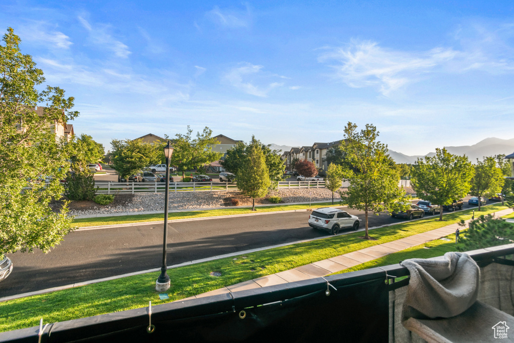 View of asphalt road featuring street lights, sidewalks, a mountain view, and curbs