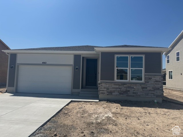 View of front of home with a garage, concrete driveway, and stone siding