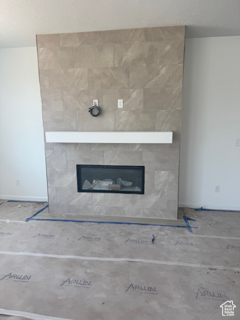 Detailed view of a tile fireplace, a textured ceiling, and baseboards