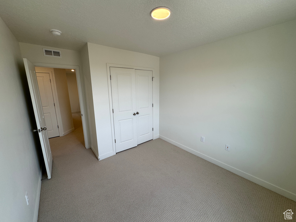 Unfurnished bedroom featuring light colored carpet and a closet