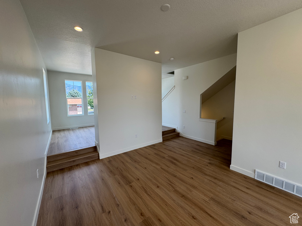 Empty room with wood finished floors, stairway, and recessed lighting