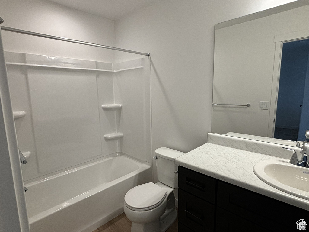 Bathroom featuring vanity, toilet, shower / bath combination, and wood finished floors