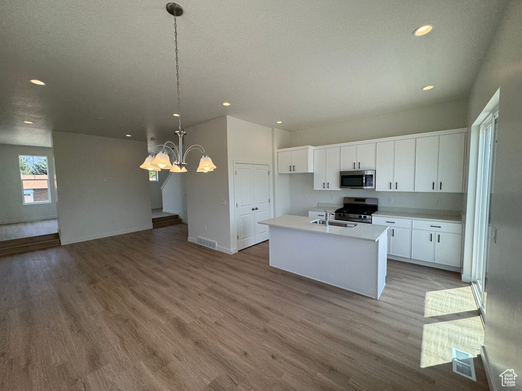 Kitchen featuring stainless steel appliances, light wood-type flooring, recessed lighting, white cabinetry, and a chandelier