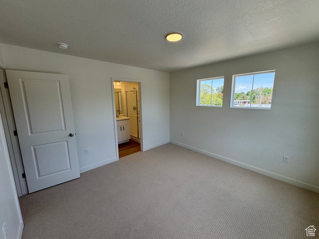 Unfurnished bedroom featuring carpet and ensuite bathroom