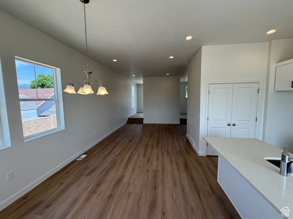 Unfurnished dining area with a chandelier, dark wood finished floors, and recessed lighting