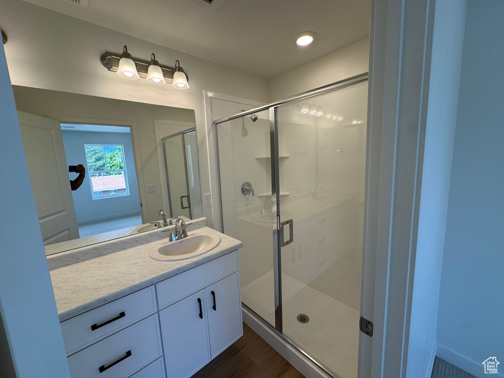 Full bathroom with vanity, a shower stall, and wood finished floors