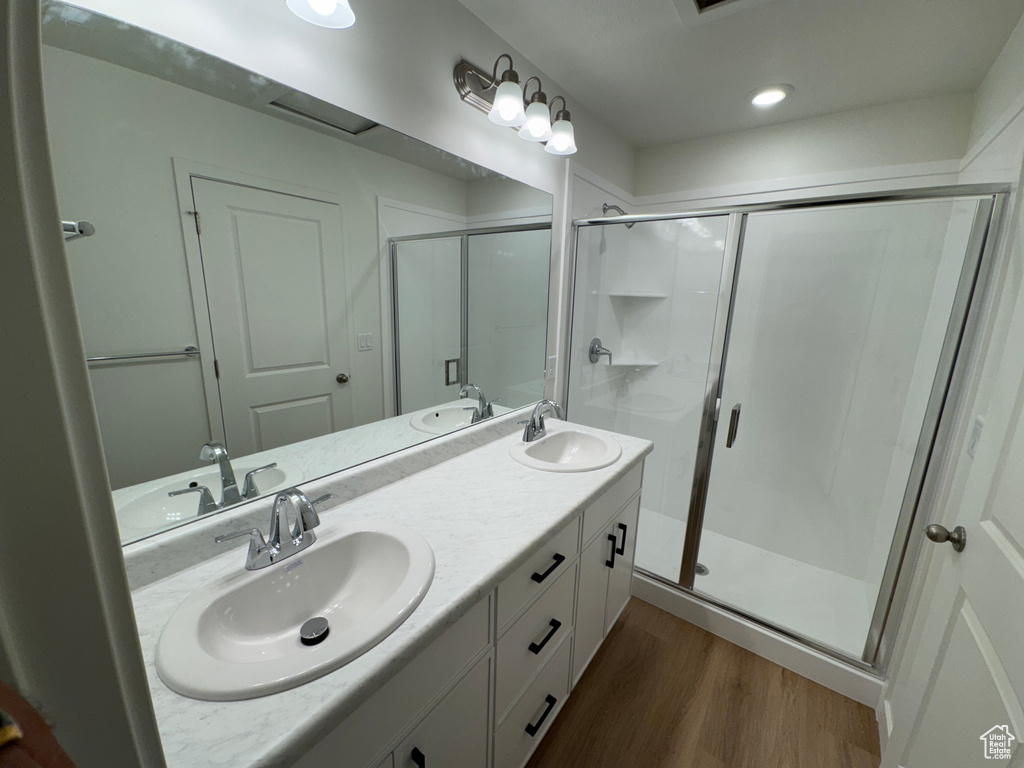 Bathroom with wood finished floors, a stall shower, and double vanity