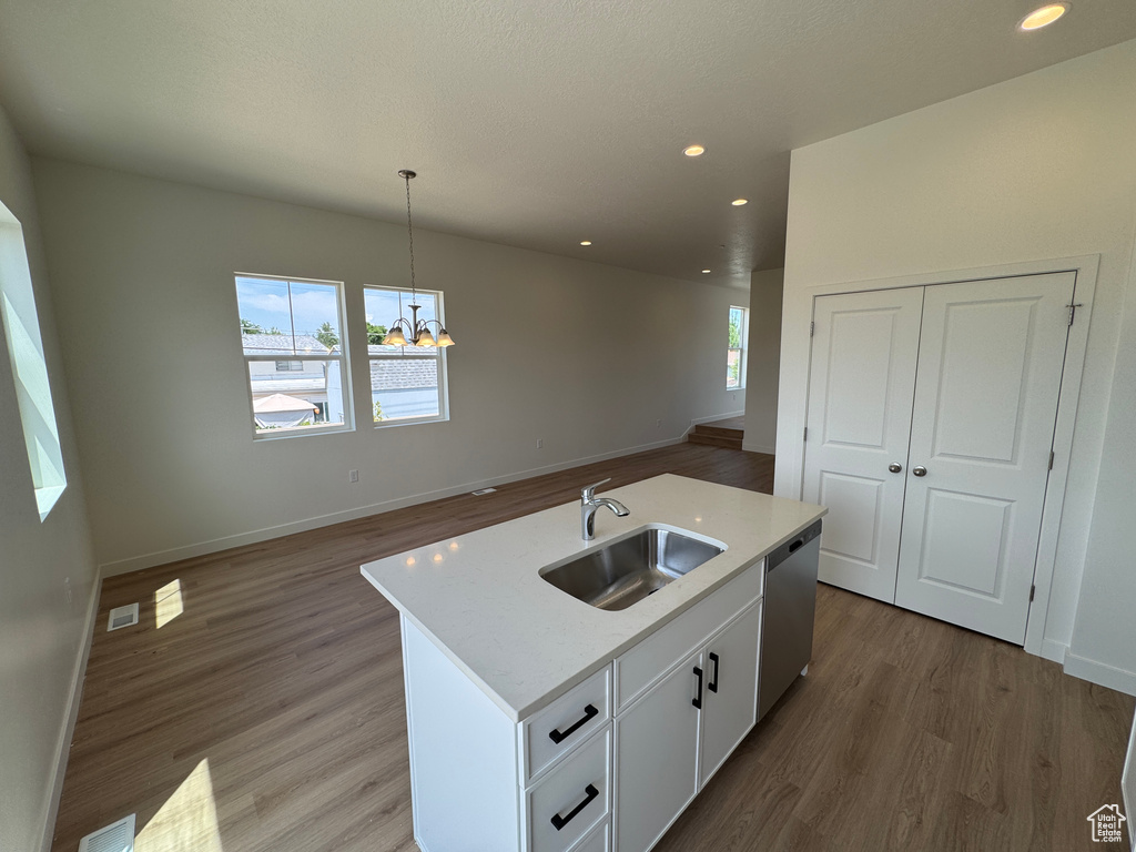 Kitchen with stainless steel dishwasher, a chandelier, light wood-style floors, open floor plan, and white cabinets