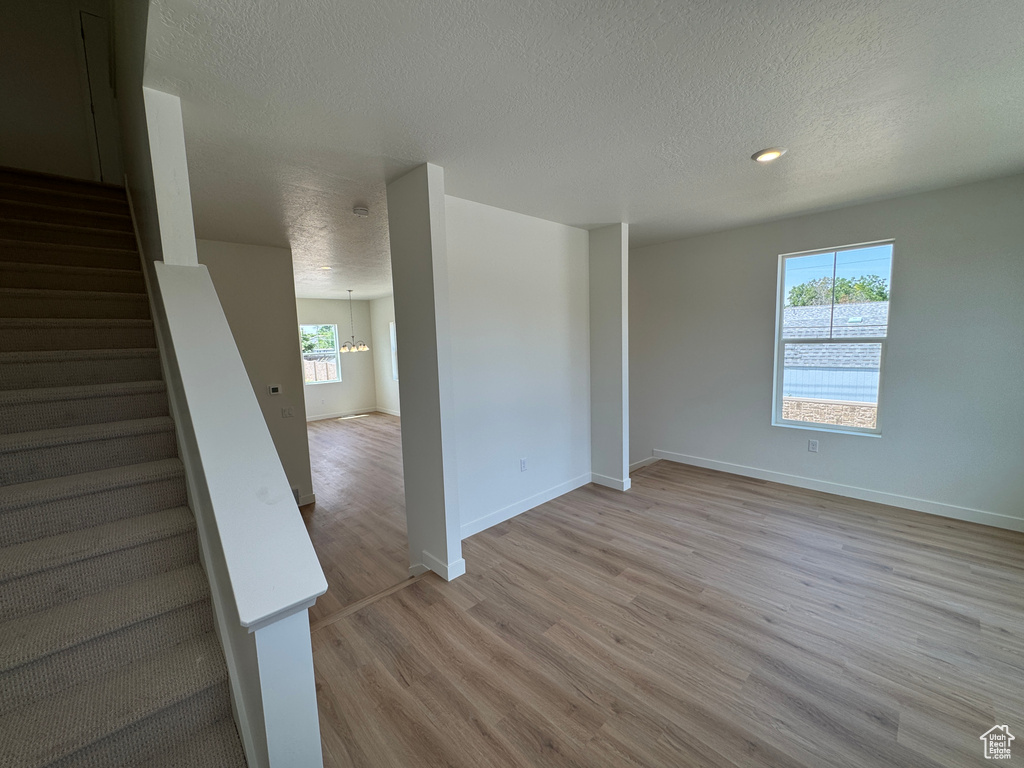Unfurnished room featuring a textured ceiling, light wood-style flooring, and stairway