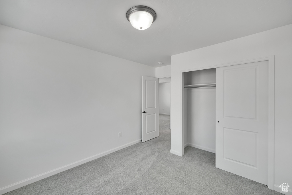 Unfurnished bedroom featuring carpet, baseboards, and a closet
