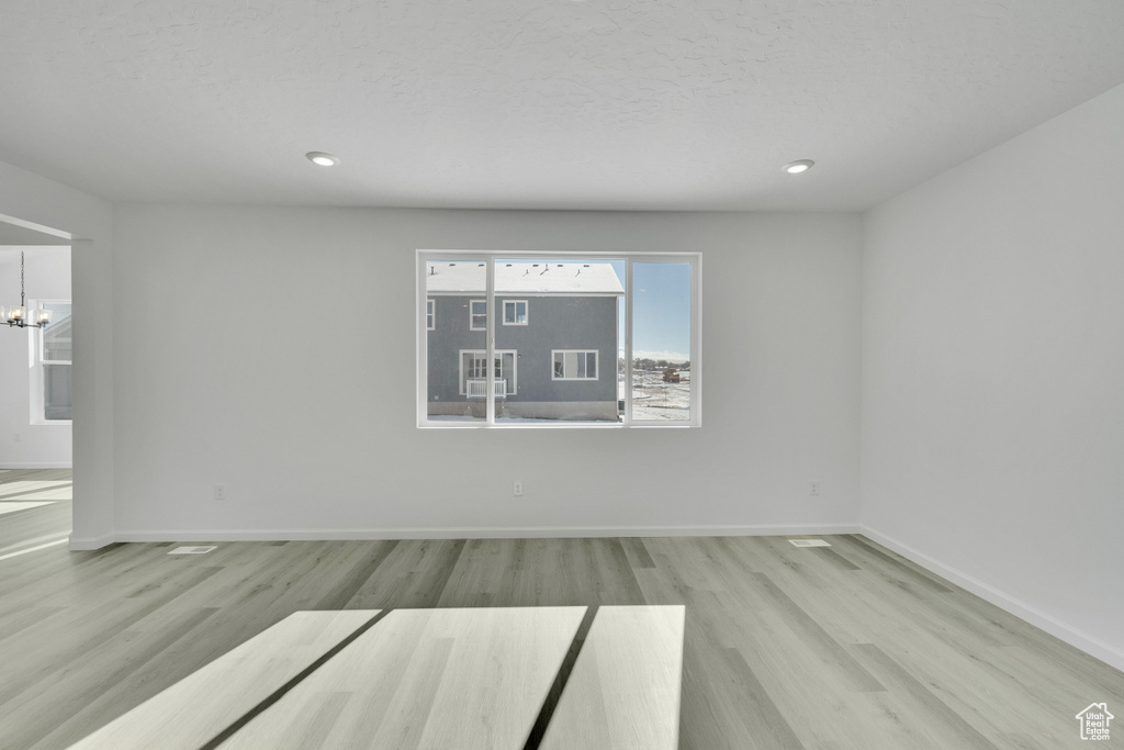 Empty room featuring wood finished floors, baseboards, a chandelier, recessed lighting, and a textured ceiling