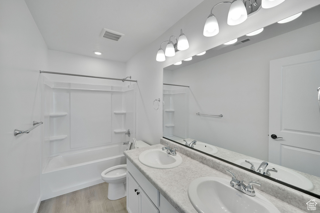 Bathroom with toilet, double vanity, wood finished floors, and  shower combination