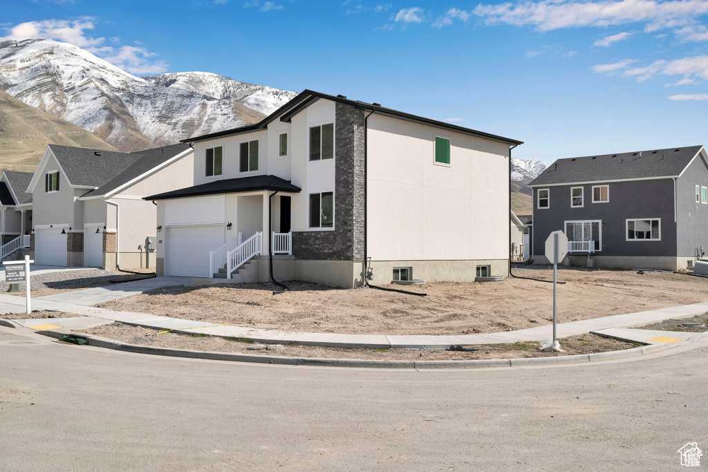 View of front of home with a mountain view, driveway, and a garage