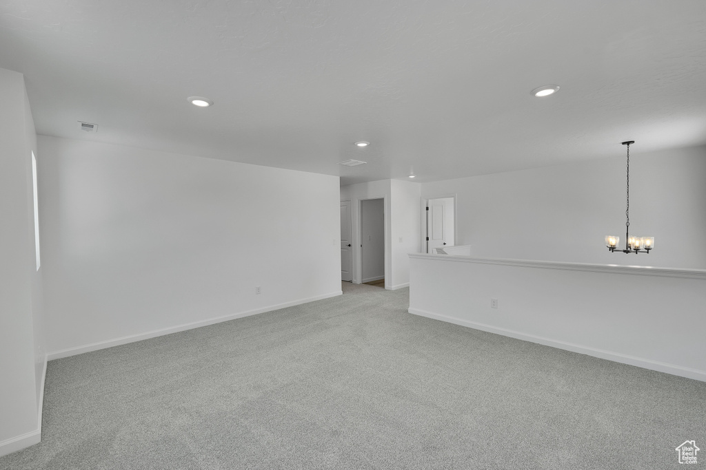 Empty room with light carpet, recessed lighting, baseboards, and a chandelier
