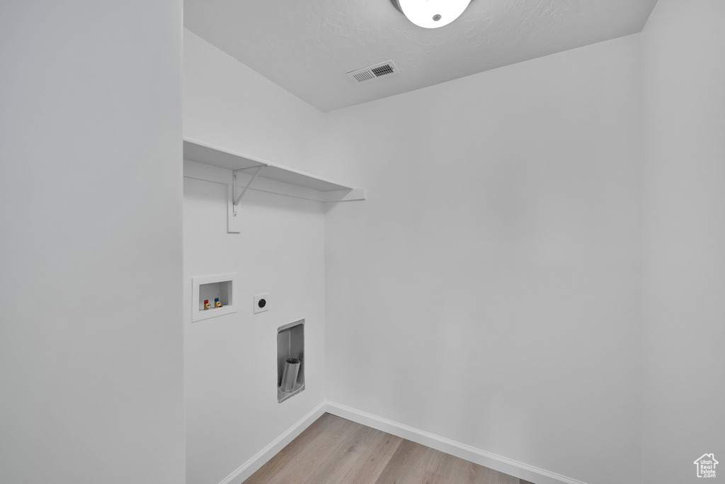 Washroom with washer hookup, light wood finished floors, baseboards, and hookup for an electric dryer