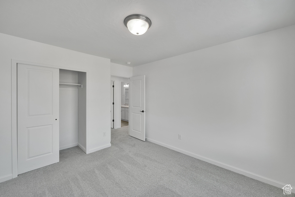 Unfurnished bedroom with light colored carpet, baseboards, and a closet