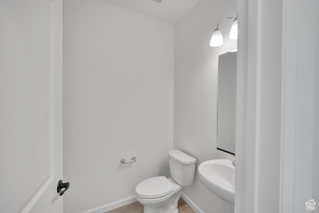 Bathroom with wood finished floors, toilet, a sink, and baseboards