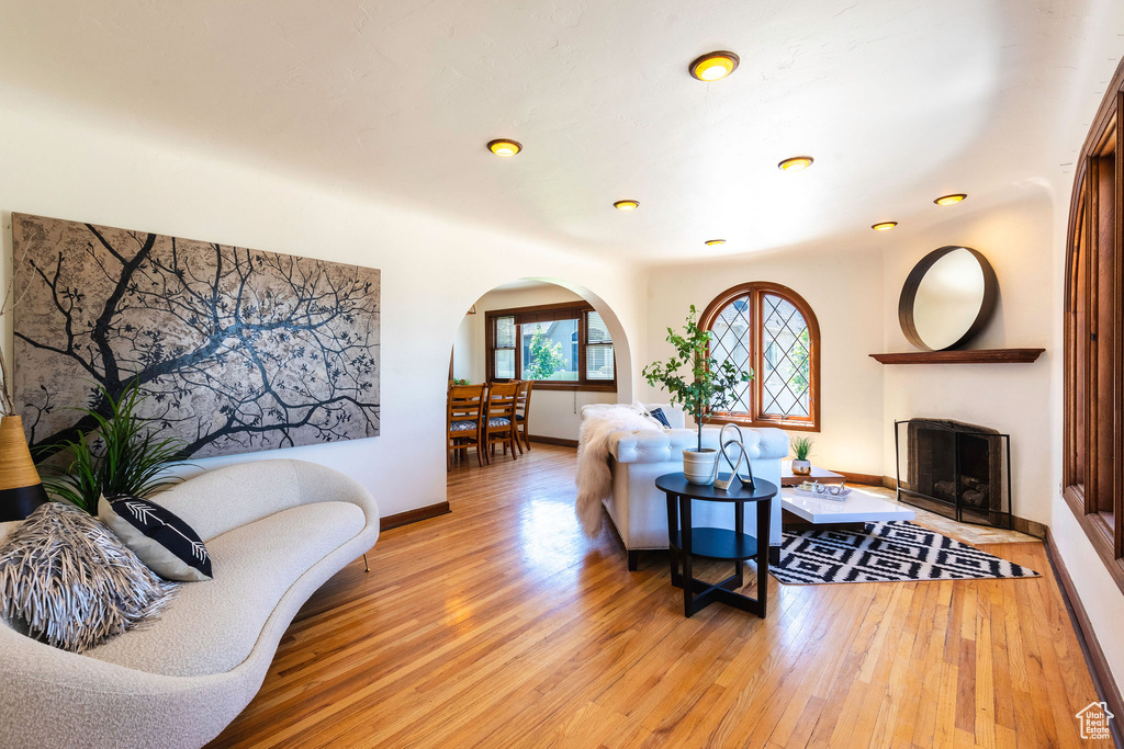 Living area featuring arched walkways, light wood finished floors, baseboards, and a fireplace