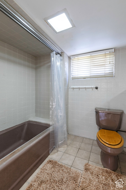 Bathroom featuring tile walls, toilet, tile patterned floors, and shower / tub combo
