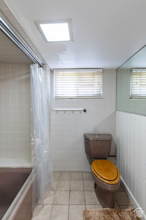 Bathroom featuring toilet, shower / bathtub combination with curtain, and tile patterned floors