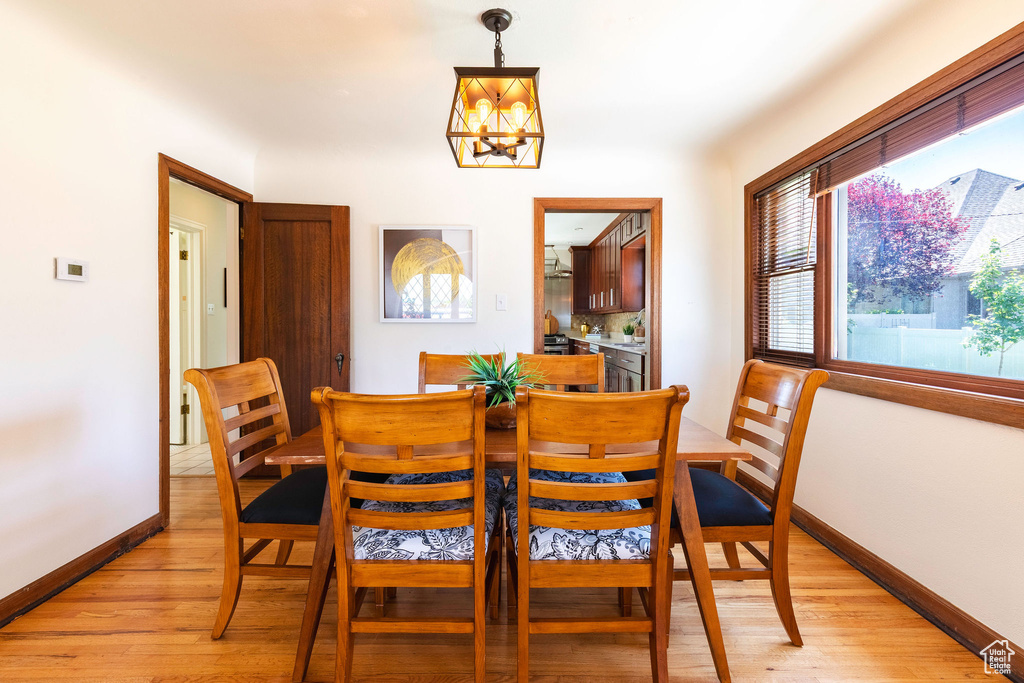 Dining area with a chandelier, light wood-style floors, and baseboards