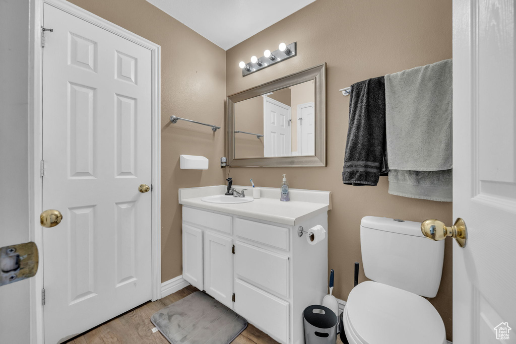 Bathroom with vanity, wood finished floors, toilet, and baseboards