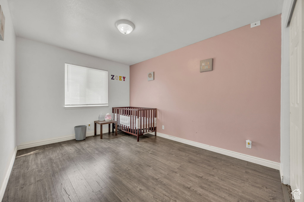 Bedroom with wood finished floors, baseboards, and a crib
