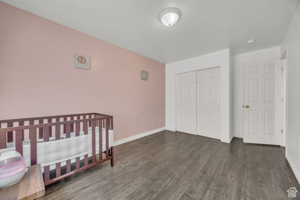 Unfurnished bedroom featuring wood finished floors, a closet, and baseboards