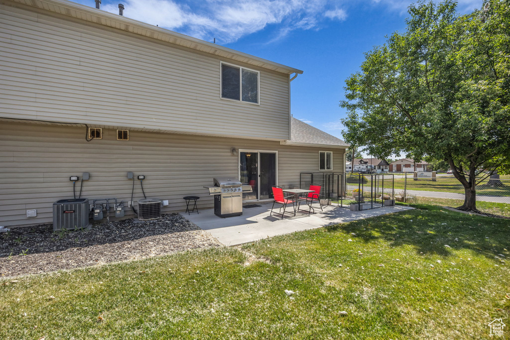 Rear view of house featuring a patio, a yard, and central AC unit