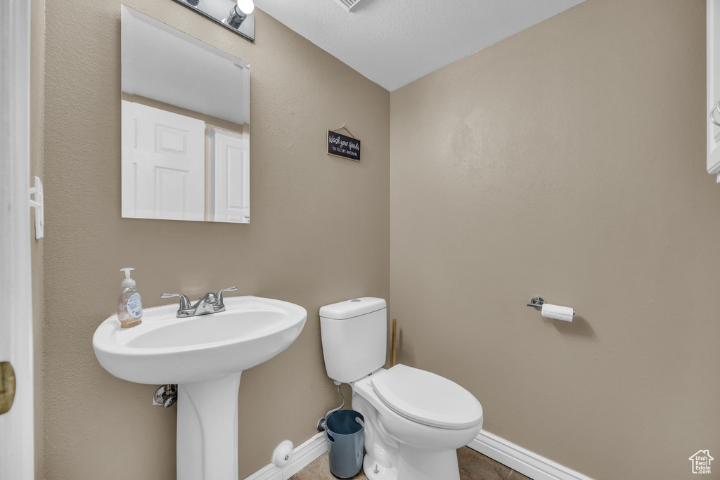 Half bathroom featuring baseboards, toilet, and tile patterned floors