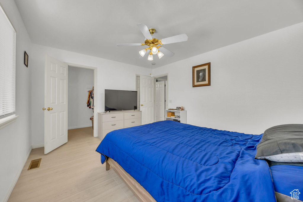 Bedroom featuring light wood finished floors, baseboards, and a ceiling fan
